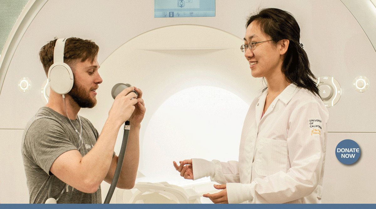 Participant wearing headphones and researcher in Prisma MRI scanner