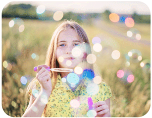 Photo of child in a field blowing bubbles