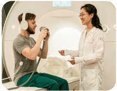 Researcher standing next to research participant sitting on MR scanner bed